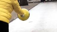Eine Person in einer gelben Jacke, die Eisstock schießt.