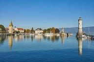 Blick über den Hafen Lindaus mit Wahrzeichen und Segelbooten an einem sonnigen Herbsttag.