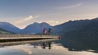 Two cyclists on a jetty at Schliersee with a mountain panorama