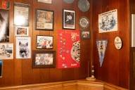 An einer holzvertäfelten Wand in der Kneipe Bierschuppen in München hängen Fotos, Kalender und Wimpel.