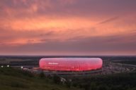 Die Allianz Arena in München leuchtet rot im Abendlicht.