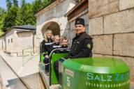 Mutter und zwei Kinder und ein Fahrer in der offenen grünen Grubenbahn des Salzbergwerks in Berchtesgaden