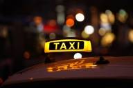 Das Schild eines Taxi leuchtet in der Nacht auf dem Dach des Fahrzeugs.