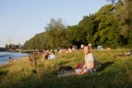 Menschen sitzen am Ufer der Isar.