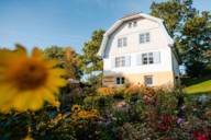 Das Münter Haus in Murnau, eine hellblau, hellgelb und weiß angestrichene Villa inmitten eines blühenden Sommergarten.