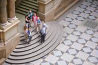 Bild einer geführten Tour durch den Münchner Justizpalast. Die Gruppe steht am Fuß der großen Freitreppe in der zentralen Halle.