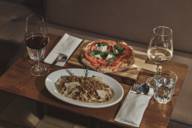 Eine Pizza und ein Pastagericht stehen auf einem Tisch in der Riva Bar in München.