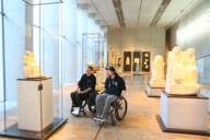 Zwei junge Rollstuhlfahrer besichtigen ein Museum in München.