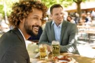 Zwei Männer sitzen mit Bier an einem Tisch in einem Biergarten in München.