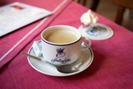 Tazza da caffè riempita con cucchiaio su un tavolo con tovaglia rossa nel ristorante tradizionale Schelling-Salon nel quartiere Maxvorstadt di Monaco di Baviera.