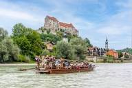 A group of visitors and musicians travel on a raft across the Salzach River in Burghausen during the Pl&auml;ttenfahrt festival.