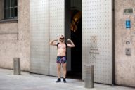 Un uomo che indossa un costume da bagno è in piedi davanti all'ingresso del Bayerische Staatskanzlei di Monaco