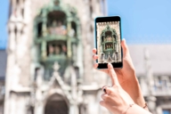 Una donna scatta una foto al Glockenspiel del Nuovo Municipio di Monaco con il suo cellulare.