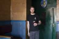 Der Gründer der Brauerei Tilmans, Tilman Ludwig, steht mit einem Glas Bier in einer Kneipe.