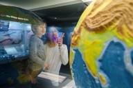 A father and his son are looking at a globe and playfully discovering the connections between the Earth, the climate and nature at the Museum of Man and Nature in Munich.