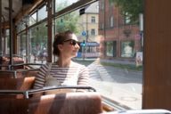 Junge Frau sitzt am Fenster in einer Tram in München.