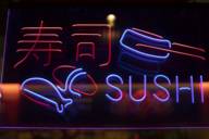 Blaue und rote Leuchtreklame mit dem Schriftzug Sushi und asiatischen Schriftzeichen
