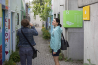 Besucherinnen fotografieren die bunten Bungalows im Olympischen Dorf in München.