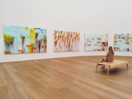 Influencerin Sarah Althaus sitzt in der Pinakothek der Moderne in München vor Gemälden.
