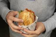 Ein Mann hält ein Sandwich von Marinas Feinkost am Viktualienmarkt in München in der Hand.