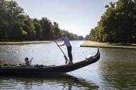 Gondolier standing with oar in hand on the gondola with guests on the Nymphenburg Canal in Munich