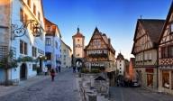 Many colourful houses on two pavements with a few people in Rothenburg ob der Tauber.
