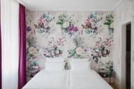 Zimmer im Moma1890 Boutique Hotel mit floralem Muster an der Wand