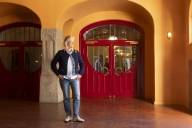 Tour guide Ina Müller is standing in front of the red Art Nouveau entrance gate at the Munich Kammerspiele.