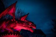 A red-lit dragon figure against a dark blue night-time background.