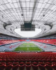 Blick auf den Innenbereich der Allianz Arena mit dem FC Bayern Logo im Hintergrund.