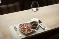 Ein Glas Wein und ein Teller Schinken und Oliven in Geisels Vinothek in München