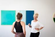Eine Galeristin und eine junge Frau unterhalten sich in einer Galerie in München.