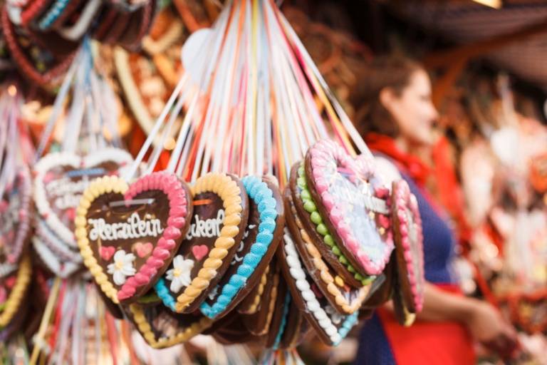 Auf dem Oktoberfest hängen mehrere bunte Lebkuchenherzen an einem Verkaufsstand