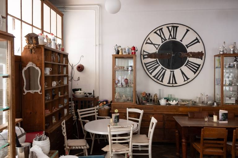 The Café Marais with the large clock face on the wall and the many wooden shelves and display cabinets with all kinds of bric-a-brac.