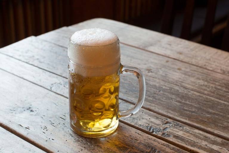 Eine Maß Bier steht auf einem Holztisch.