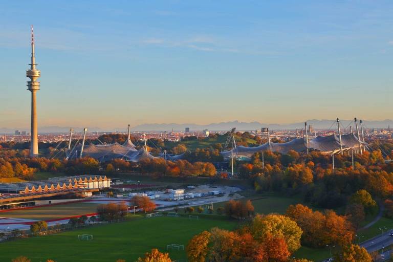 Der Münchner Olympiapark im Herbst mit den Alpen im Hintergrund.