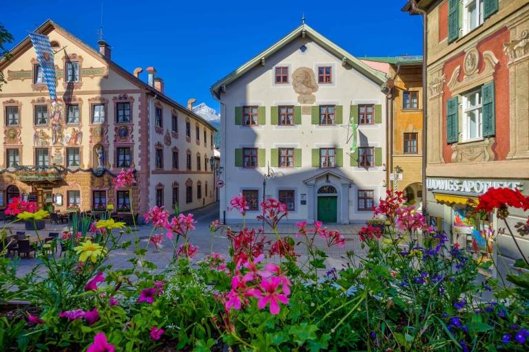 Mehrere bunte Häuser mit Blumen im Vordergrund in Garmisch Partenkirchen.