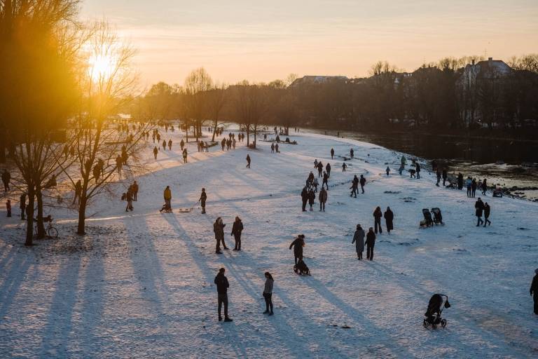 People walking along the Isar near the Reichenbach Bridge in the evening sun in winter.