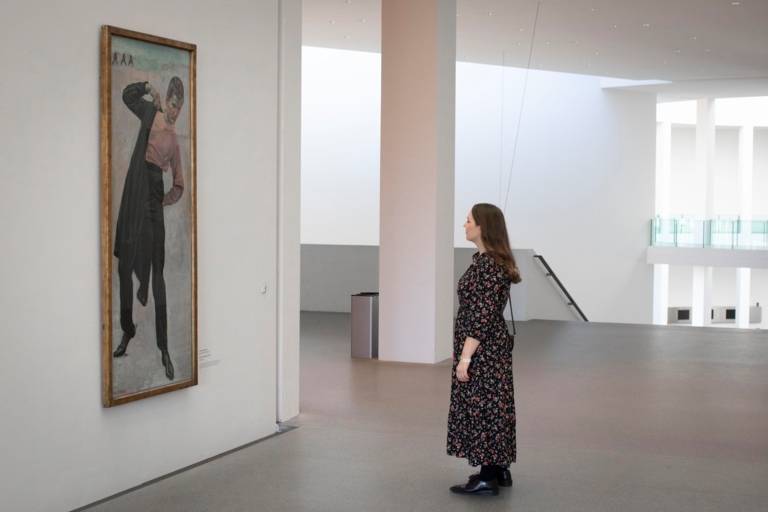A young woman stands in front of the painting Jenenser Student by Ferdinand Hodler in the Pinakothek der Moderne in Munich