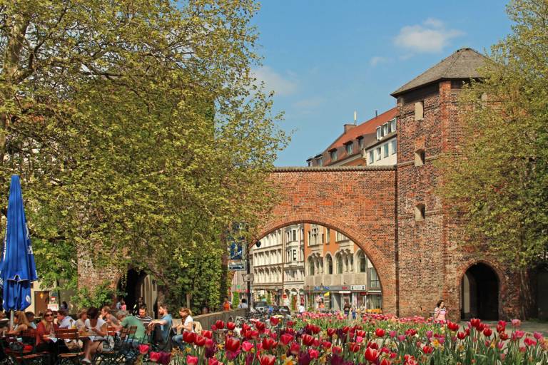 Vor dem Sendlinger Tor in München sitzen Leute auf einer Restaurantterrasse