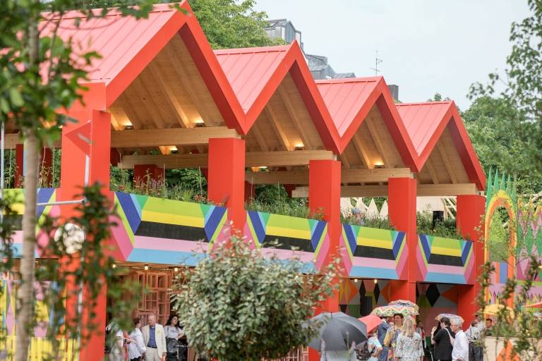 A few people are standing on the colourful grounds of FLUX next to the Pinakothek der Moderne