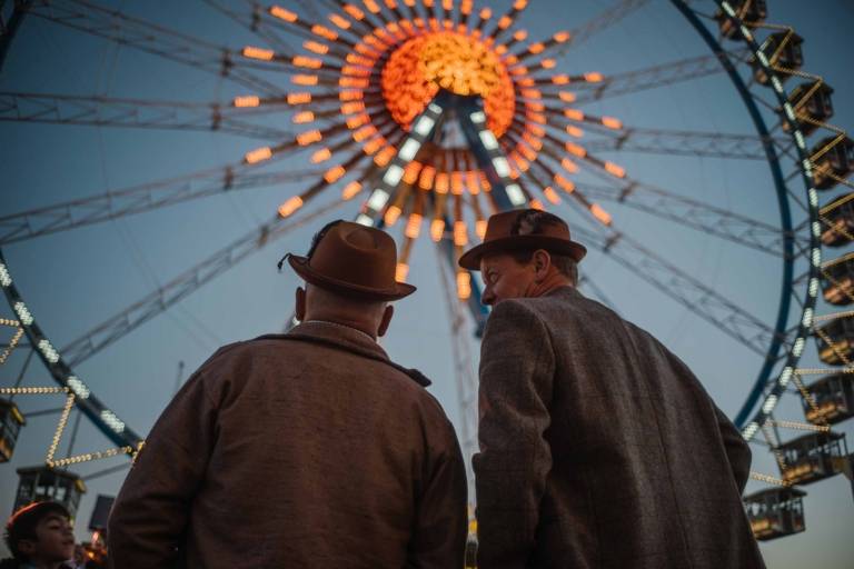 Zwei Männer vor dem Riesenrad auf dem Oktoberfest in München.
