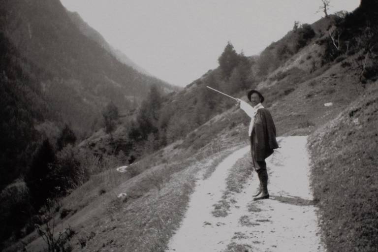 Foto einer schwarz-weiß Aufnahme, auf der ein Mann mit Hut in den Bergen spazieren geht.