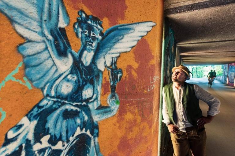 Münchner mit Trachtenhut und Lederhose betrachtet Graffiti