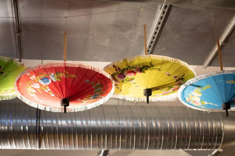 Four Asian umbrellas in red, yellow, green and blue as ceiling decoration in a restaurant in Munich's Werksviertel.
