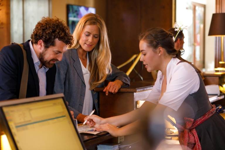 Ein Mann und eine Frau checken in einem Hotel in München ein.