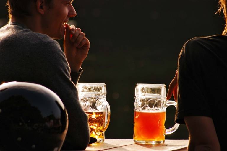 Zwei Bierkrüge leuchten im Abendlicht in einem Biergarten in München.