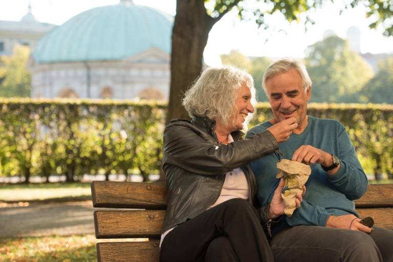 Ein älteres Paar isst Maronen auf einer Bank am Hofgarten in München.