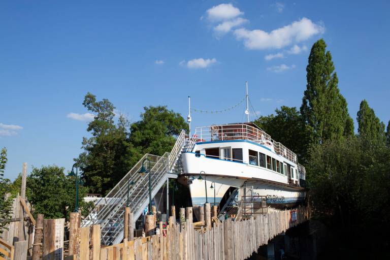 A disused excursion boat is accessible via a metal staircase.