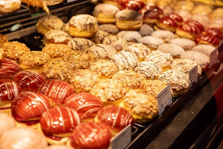 Several types of doughnuts are on display in a bakery